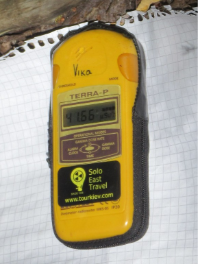 A yellow Geiger counter in front of a white piece of paper.